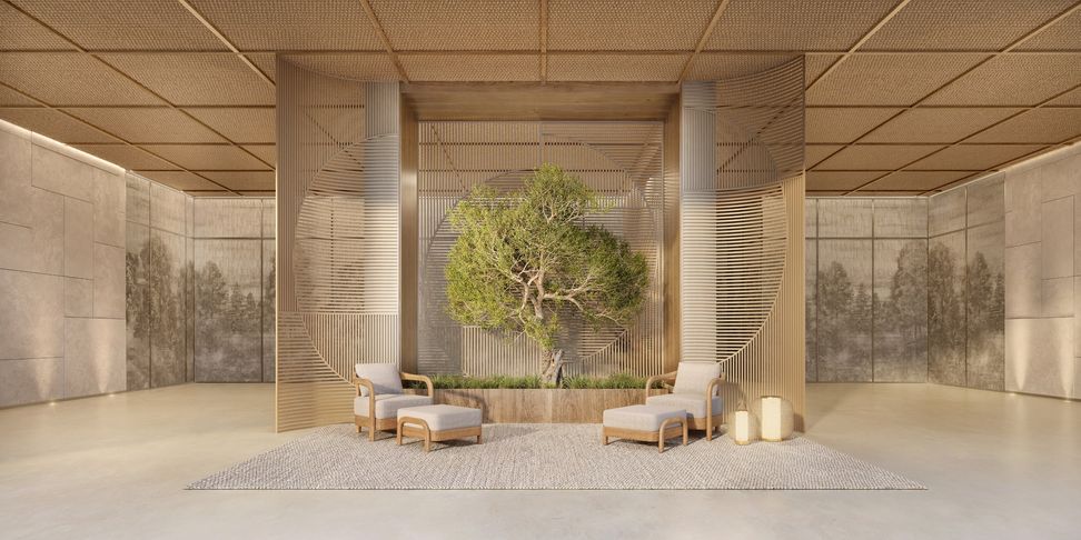Salão do clubhouse com pé-direito alto, uma árvore ao centro e poltronas junto ao jardim interno