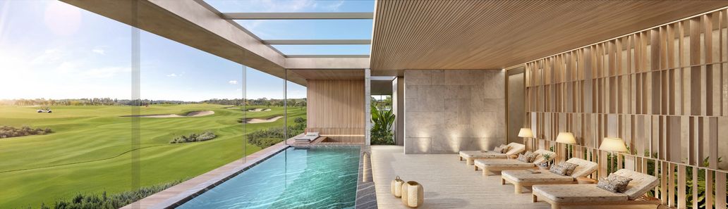 Piscina coberta do wellness em salão de pé-direito alto, com parede de pedra e vista aberta para o campo de golfe