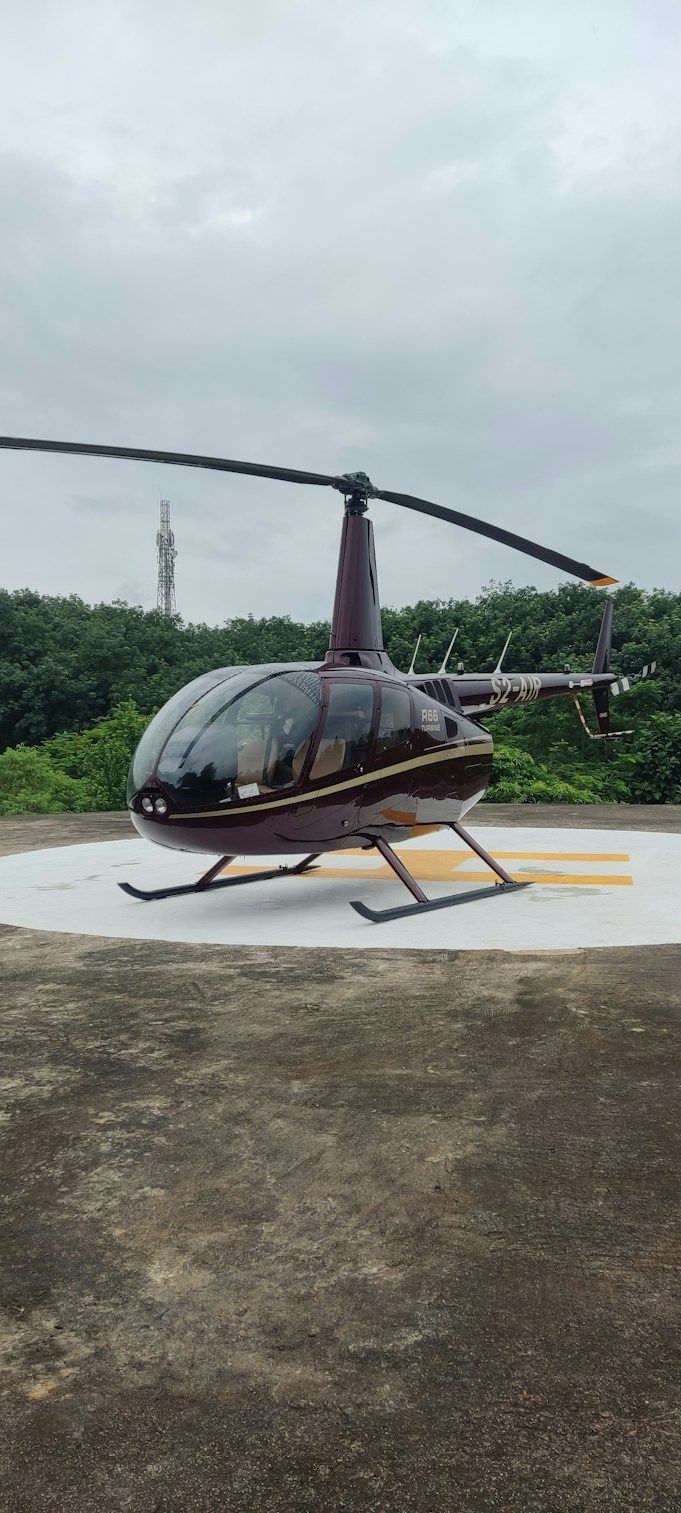 Helicóptero pousado em um heliponto entre a mata, visto de cima